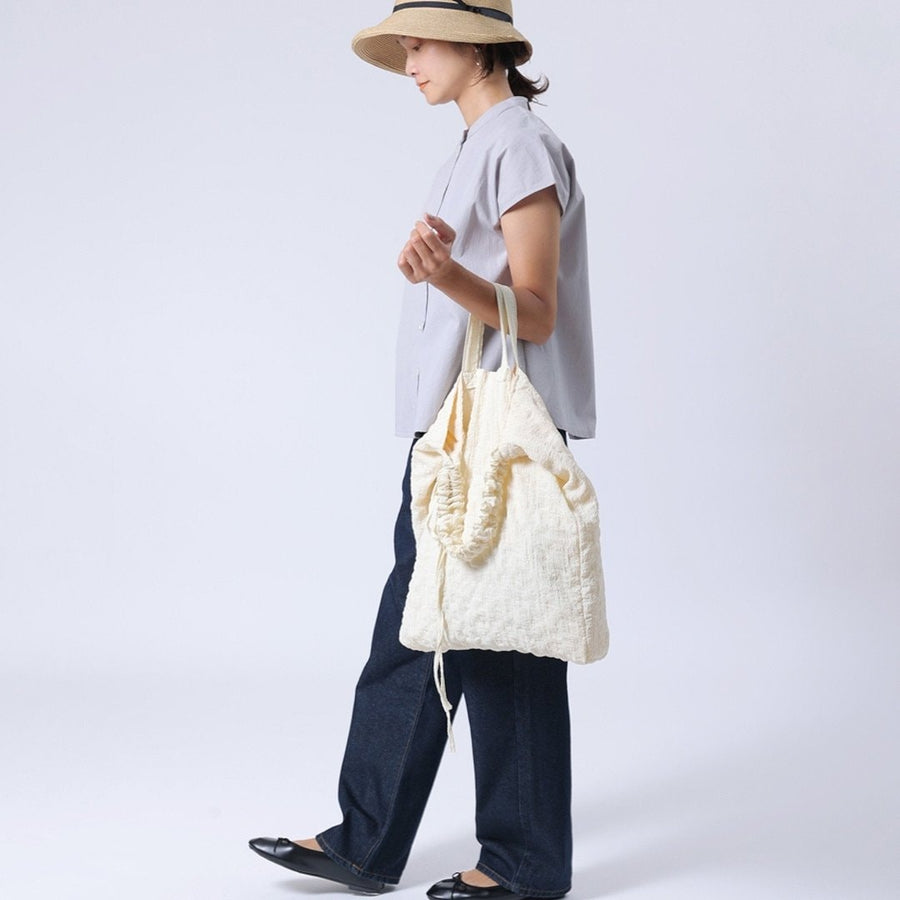 A crumpled drawstring gathered handle bag