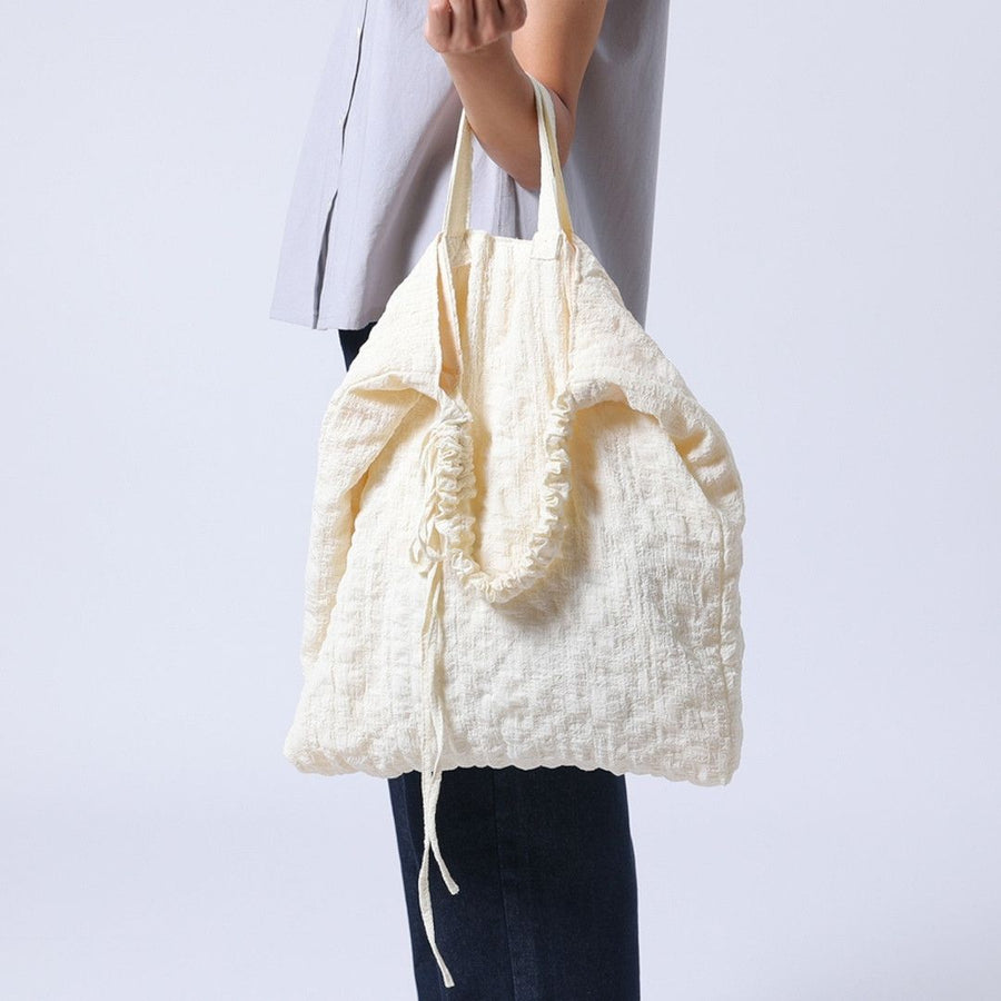 A crumpled drawstring gathered handle bag