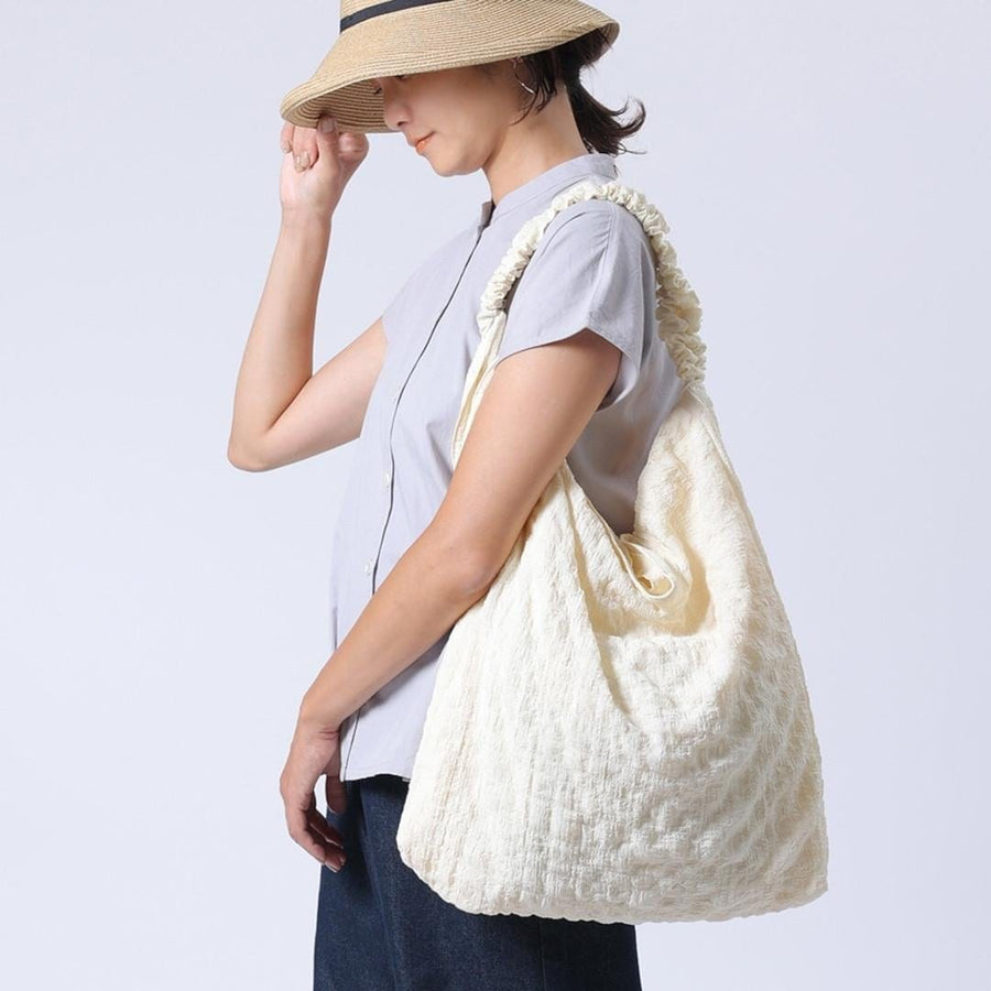 A crumpled drawstring gathered handle bag